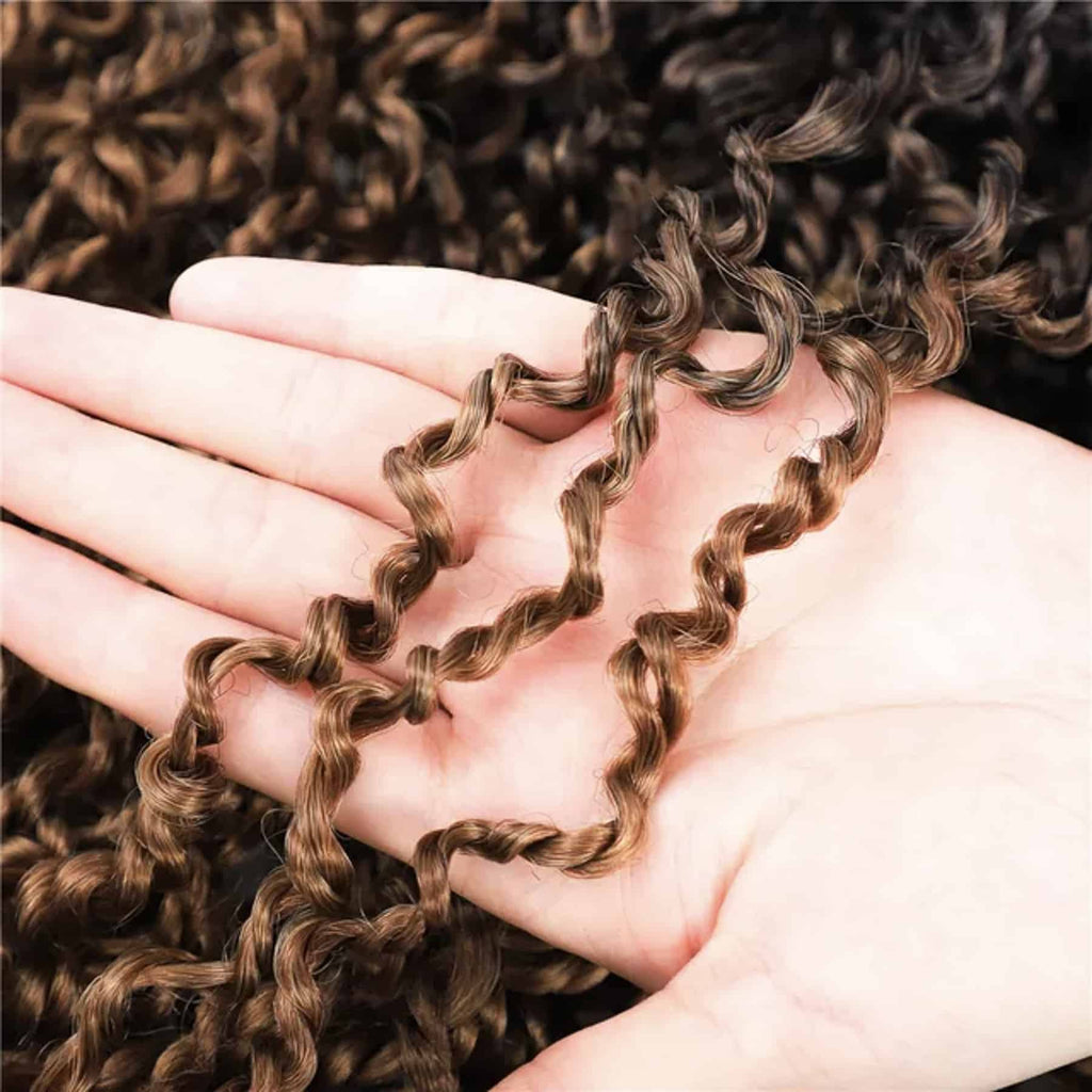 Närbild på flätor (braids) där en hand håller i dem, vilket framhäver den täta strukturen och detaljerna i flätorna, som har en naturlig och voluminös look.