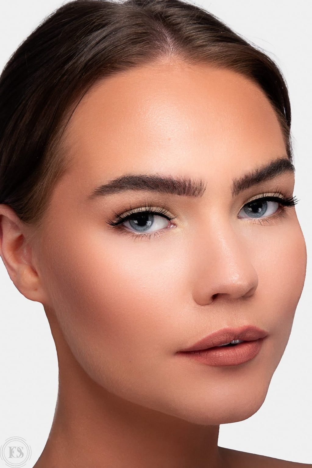 Kvinna med naturlig makeup och diskreta lösögonfransar som framhäver ögonens form och ger en elegant, mjuk look.