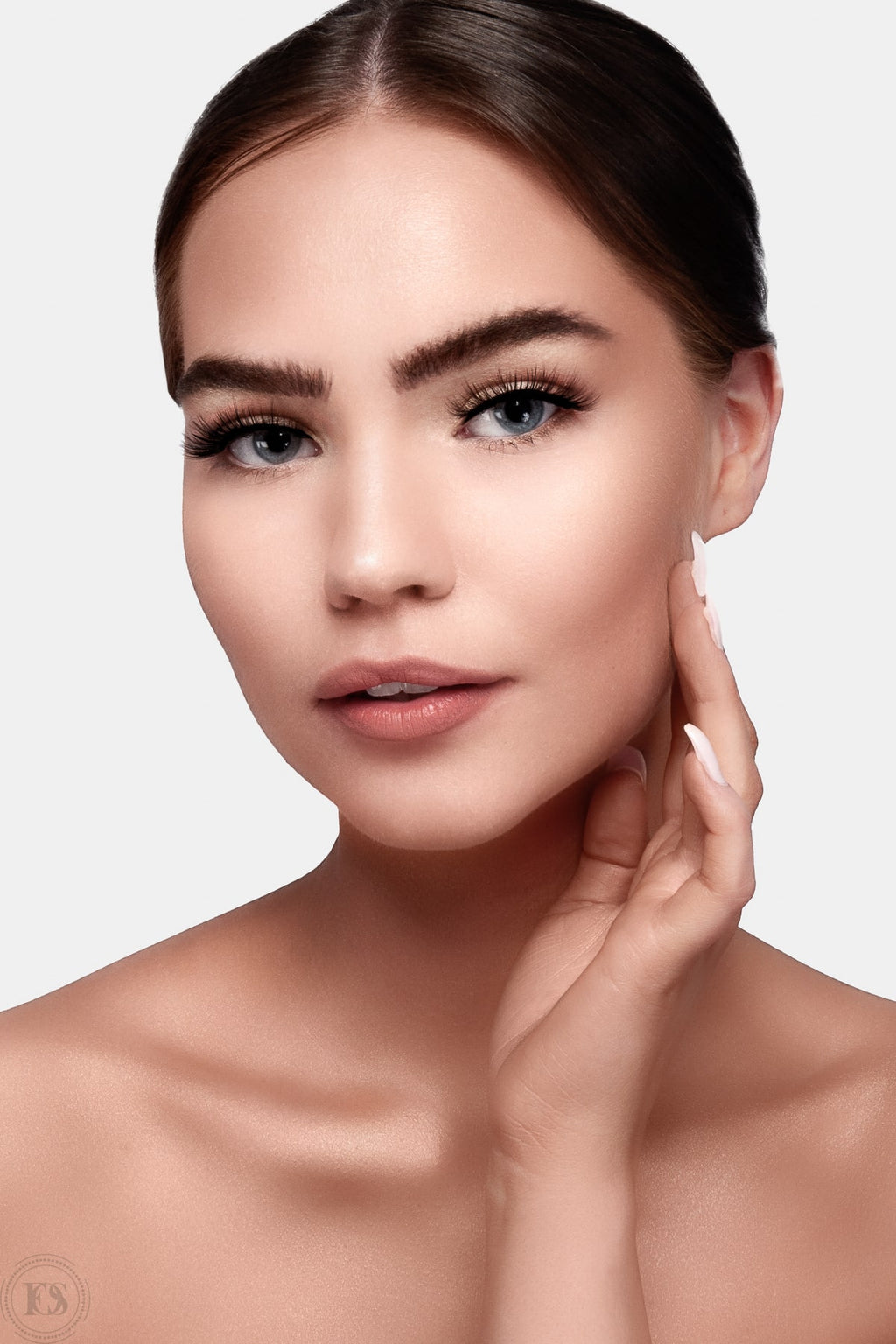 Kvinna med naturlig, elegant makeup och mjuk lyster i huden, bär subtila lösögonfransar som framhäver ögonen på ett sofistikerat sätt.