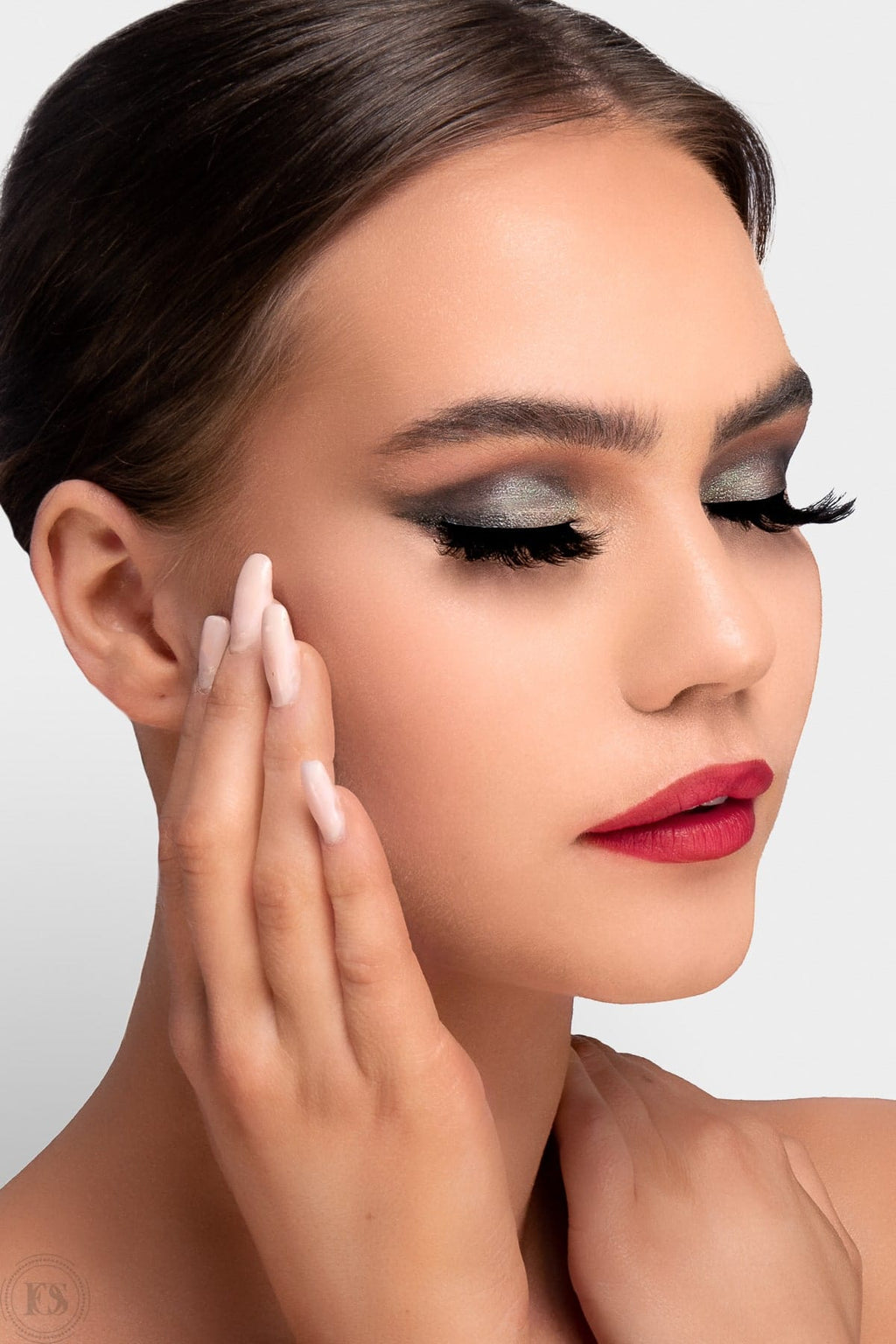 Kvinna med elegant makeup i röd läppfärg och skimrande grå ögonskugga, bär fylliga lösögonfransar som ger en dramatisk och glamorös look.