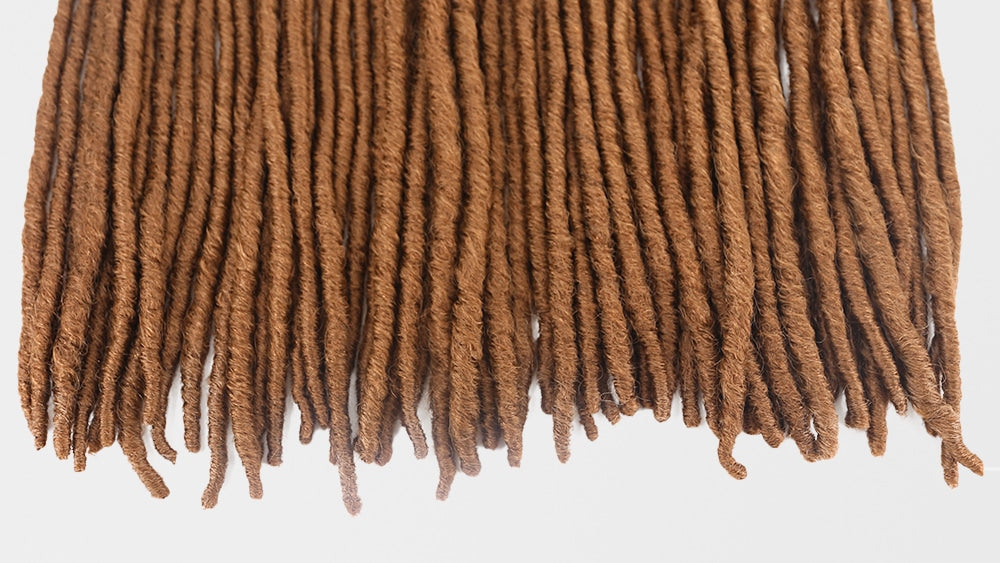 Faux locs i färg 27, med en vacker gyllene nyans som ger en varm och solkysst look, perfekt för en naturlig och bohemisk stil.