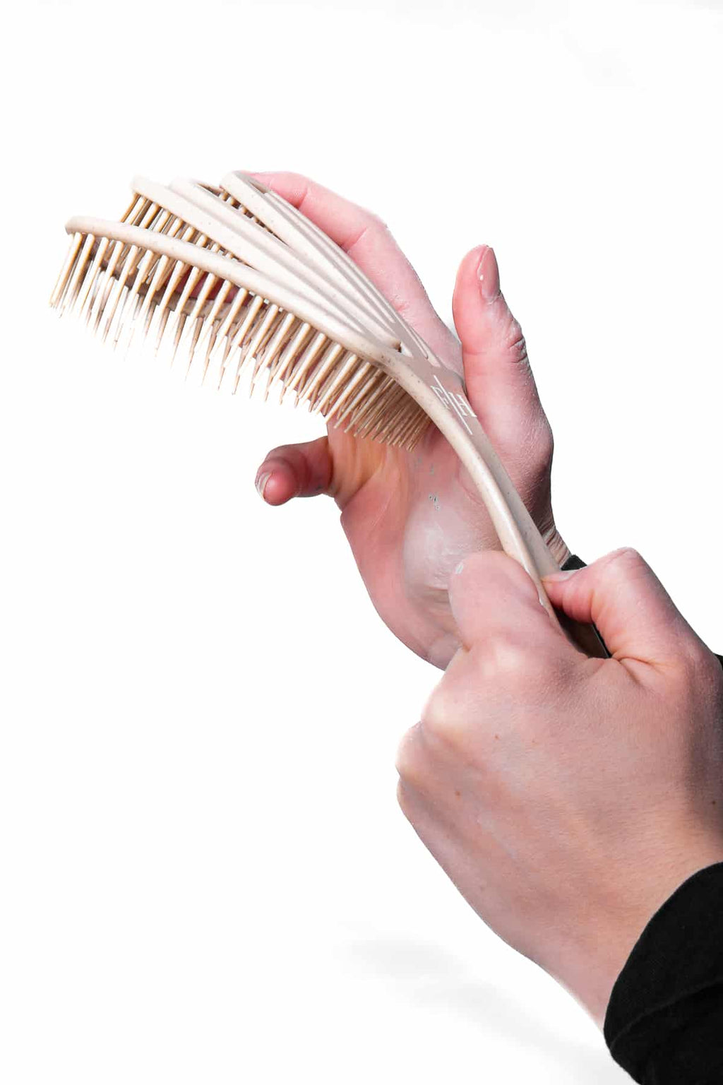 Beige utredande hårborste, detangler hålls i av modell.