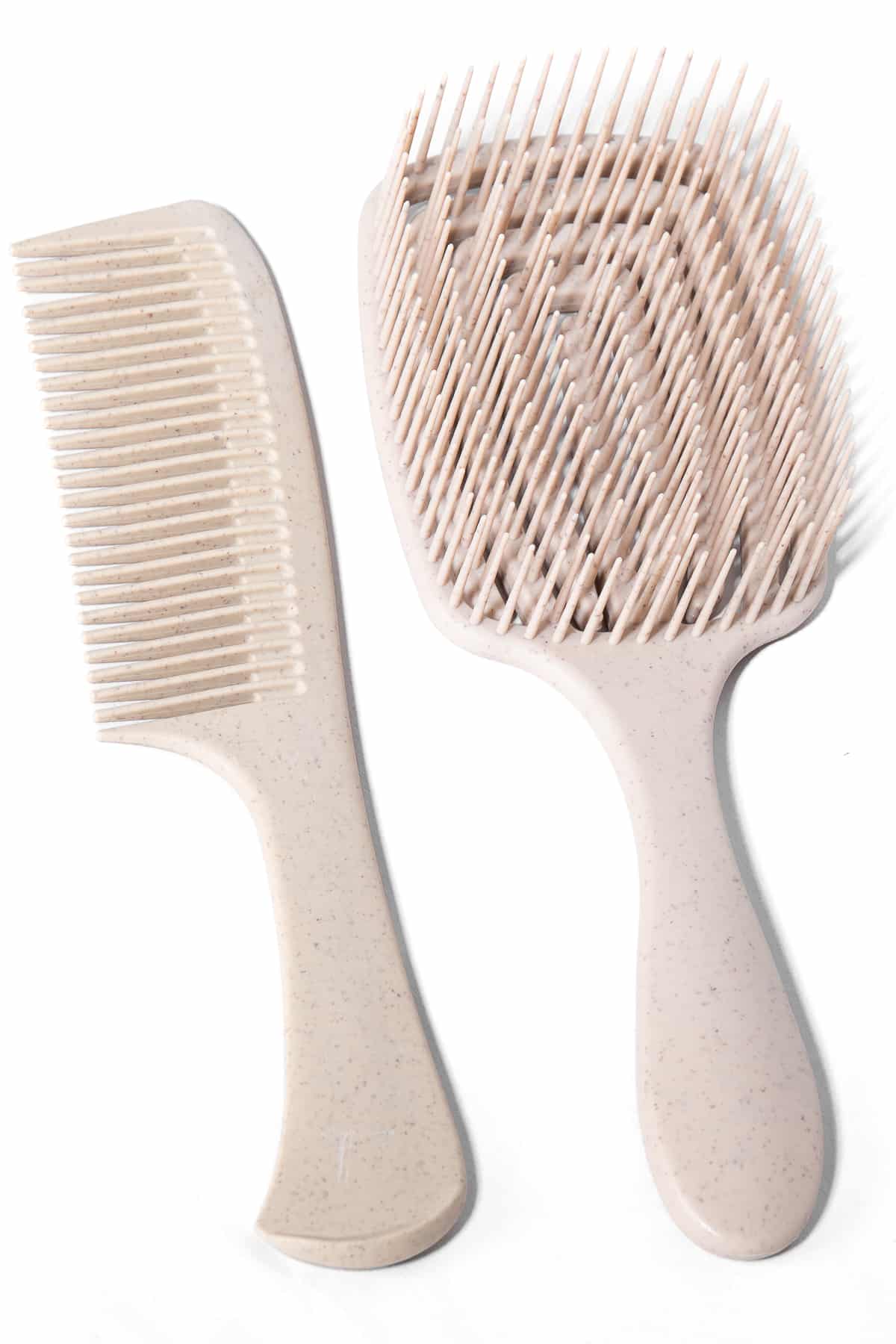 En bredtandad kam och en detangler i beige natur färg ligger bredvid varandra mot vit bakgrund.