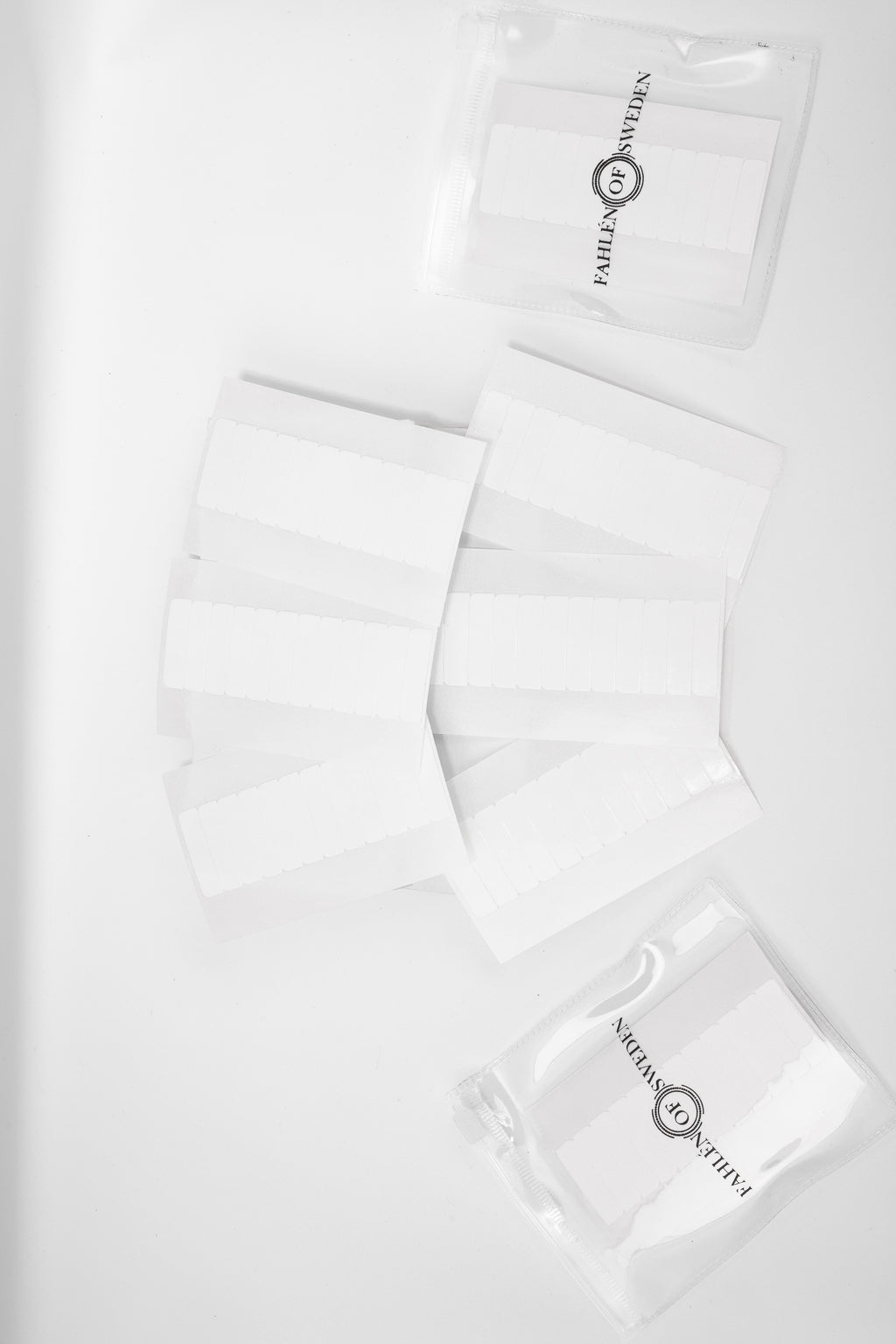 Refill-tejp för tape extensions, visade i genomskinliga Fahlén of Sweden påsar och lösa ark med vita tejpremsor på ljus bakgrund.