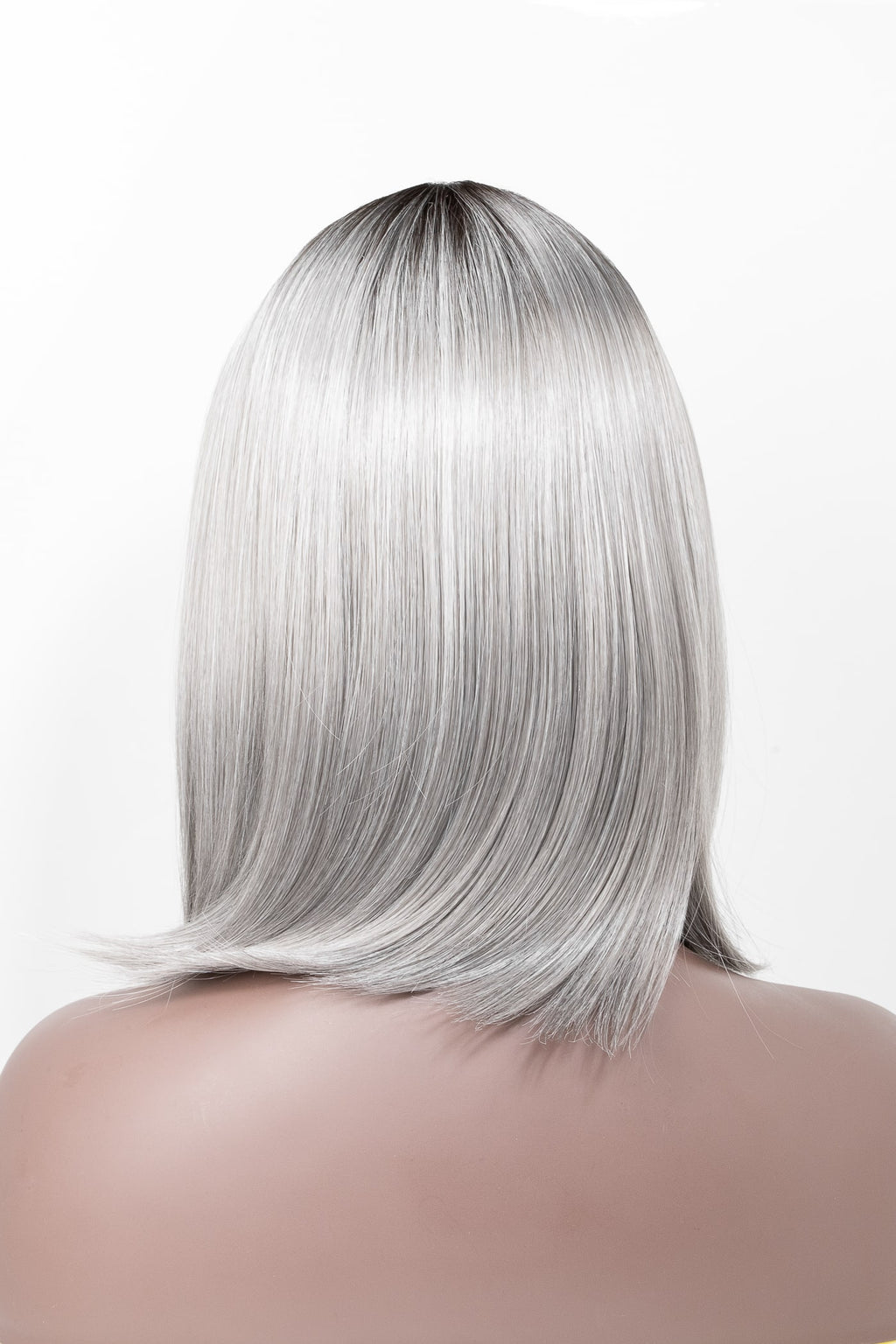 Kort bobfrisyr i silvrig ton med mörk rot och mjuk glans. Peruken har naturlig fallning och slät textur som formar en elegant siluett bakifrån.