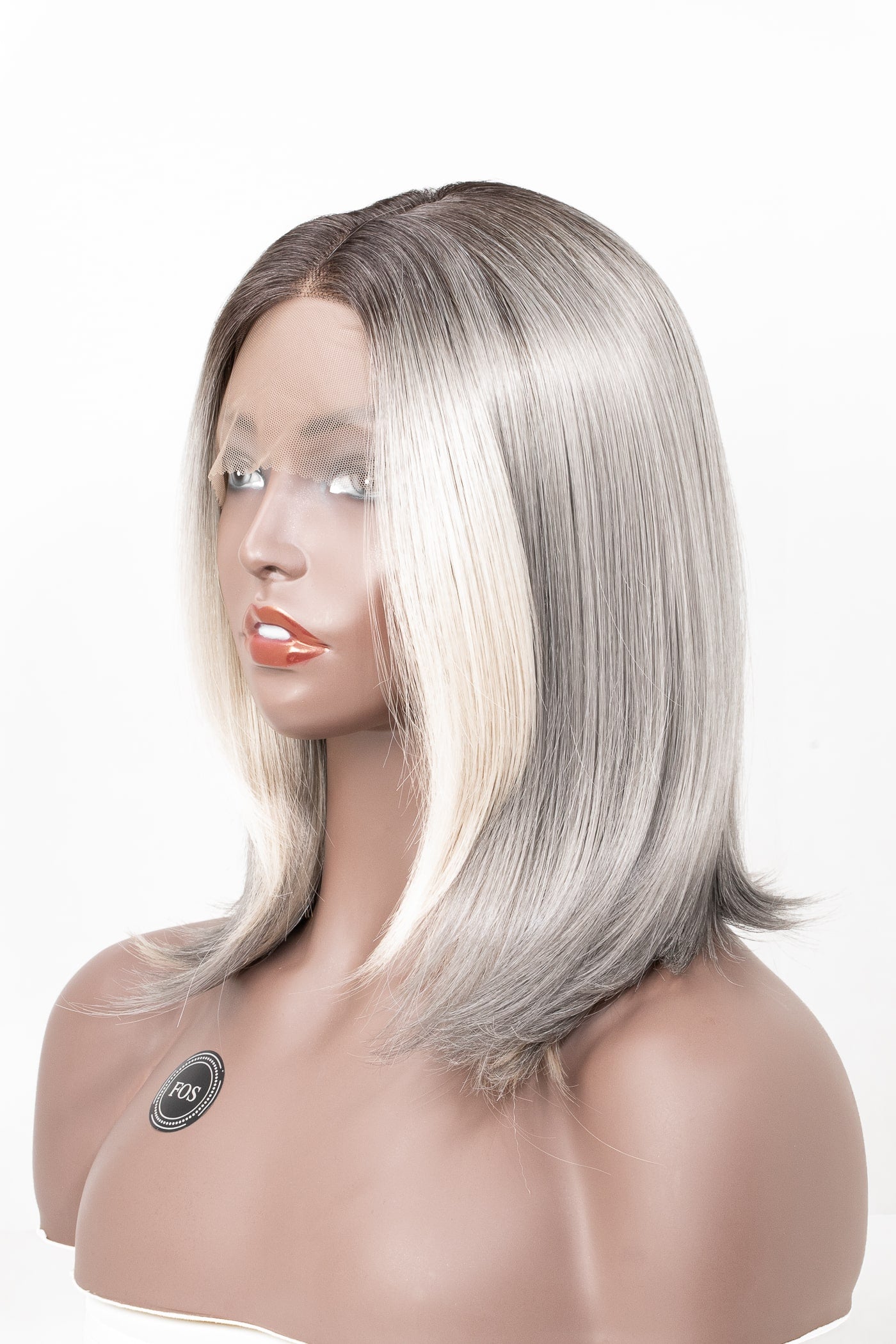 Kort peruk i elegant bobfrisyr med mjuk mittbena. Färgen övergår från askbrun till ljusblond med naturlig glans och slät textur.