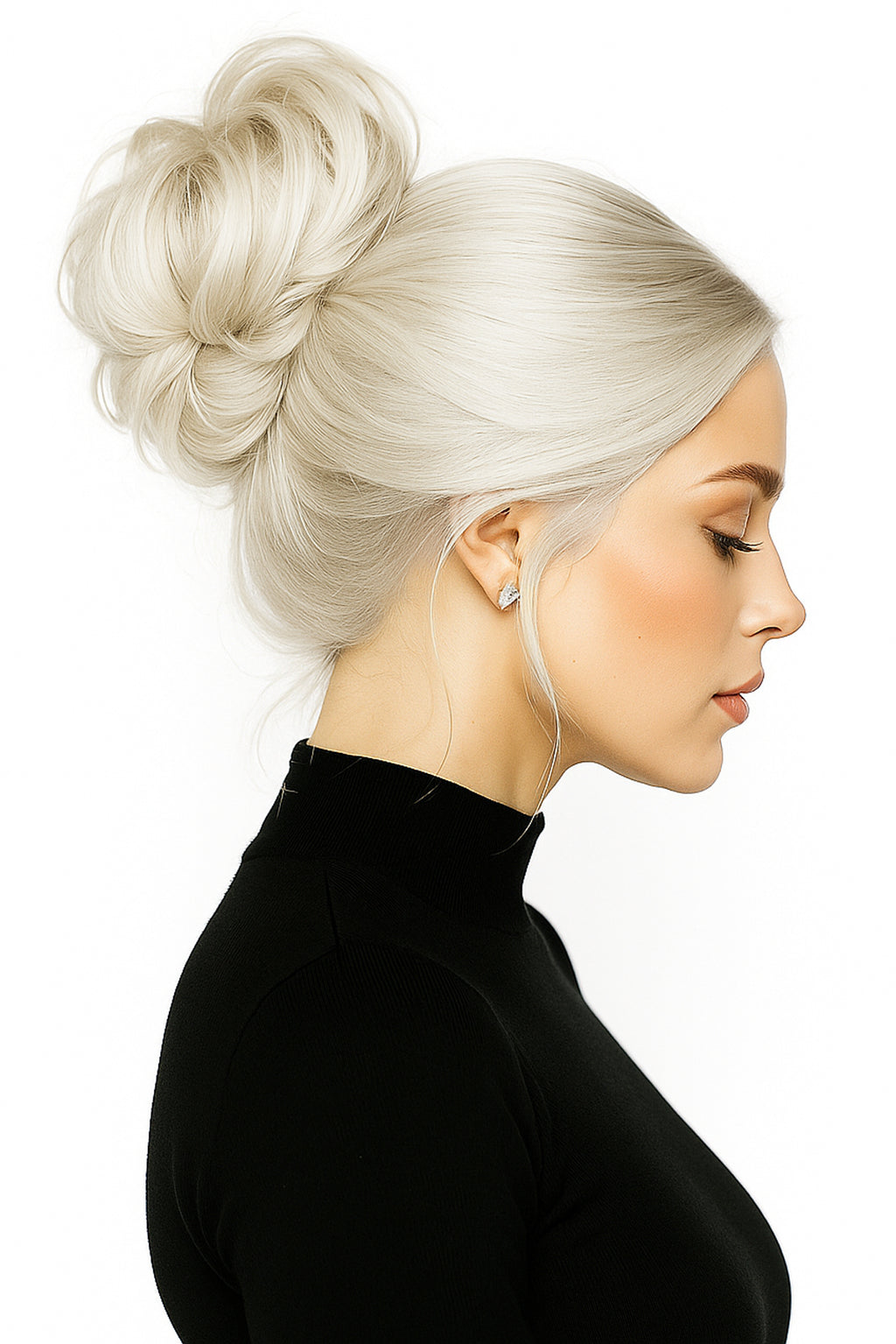 Blond kvinna med volymöst hår uppsatt i en messy bun, iförd svart polo, hårfärg 613