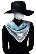 Mannequin bär elegant ljusblå scarf med ljusrosa mönster löst över axlarna.