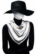Mannequin i svart hatt och polotröja bär en elegant scarf med diagonala ränder i vitt, svart, beige och brunt, knuten löst runt halsen.