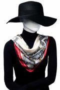 Elegant scarf med mönster i vitt, svart, guldgul och röd, hängande löst runt halsen.