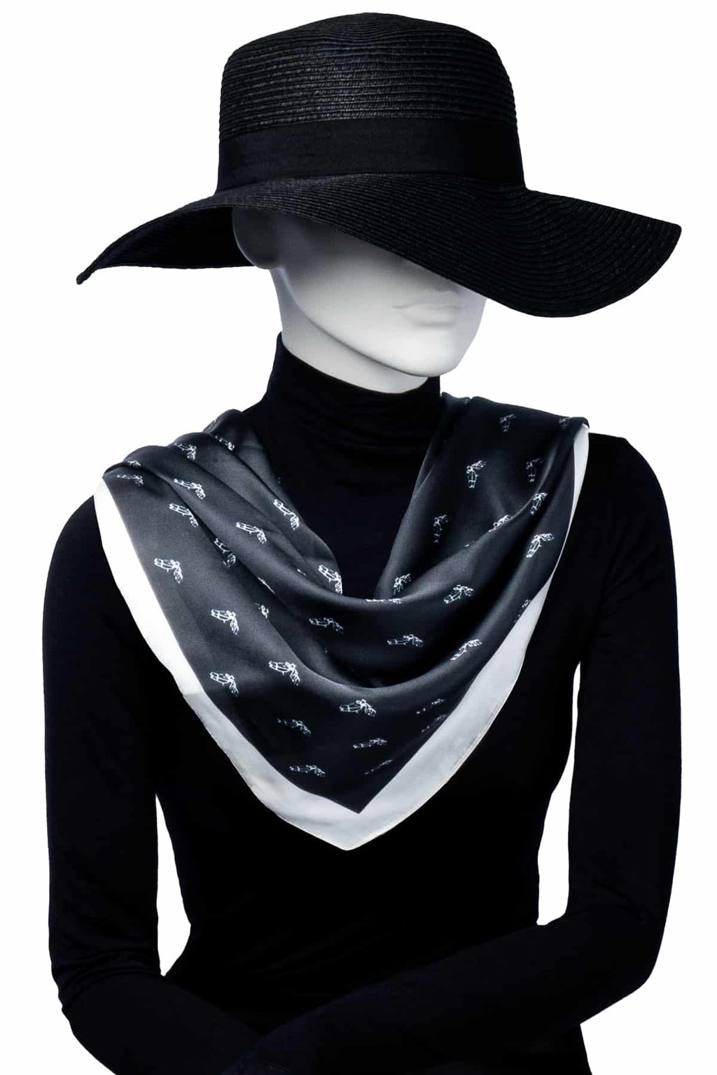 Mannequin bär svart scarf med vit kant och subtilt mönster. En stilren och tidlös accessoar i silkesliknande material.