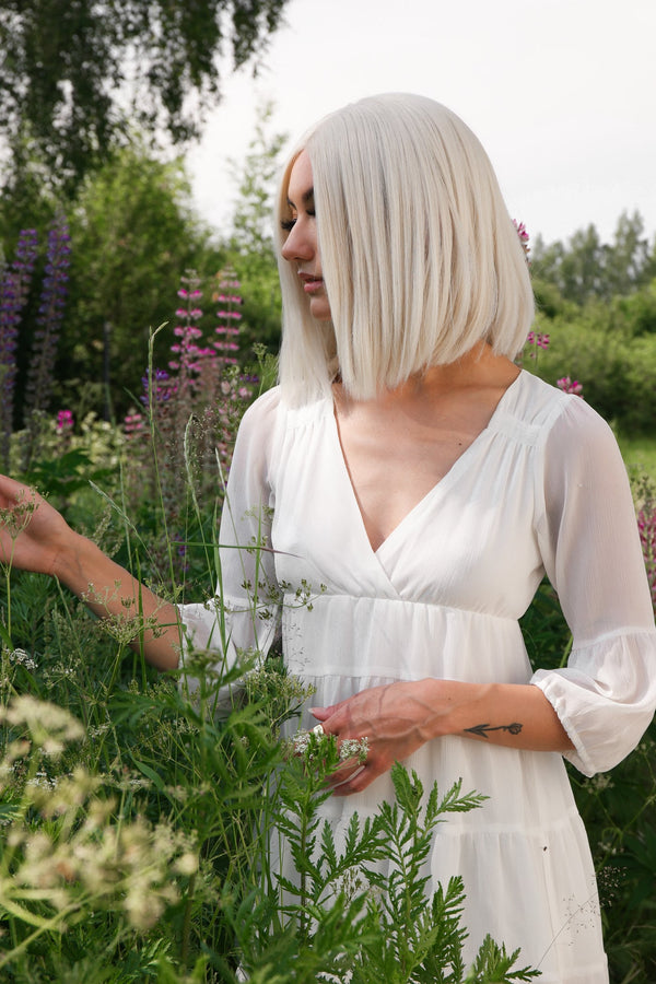 Kort peruk i isblond nyans med rak bobfrisyr och mittbena. Silkeslen textur som ger en naturlig glans och elegant, modern siluett.