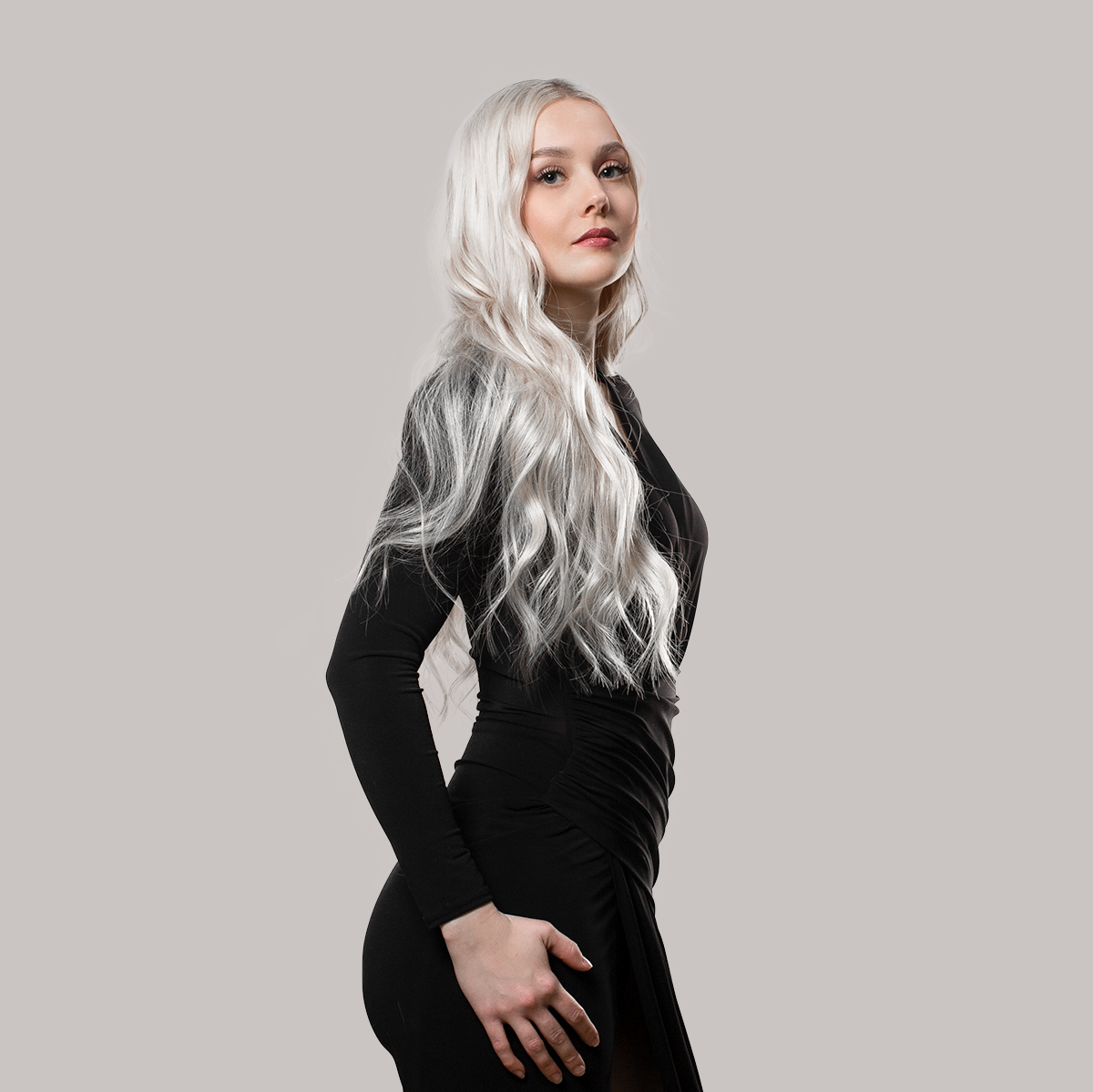 långt, vågigt och platinumblont hår bär en elegant svart klänning och visar upp ett naturligt resultat med tejp hårförlängning.