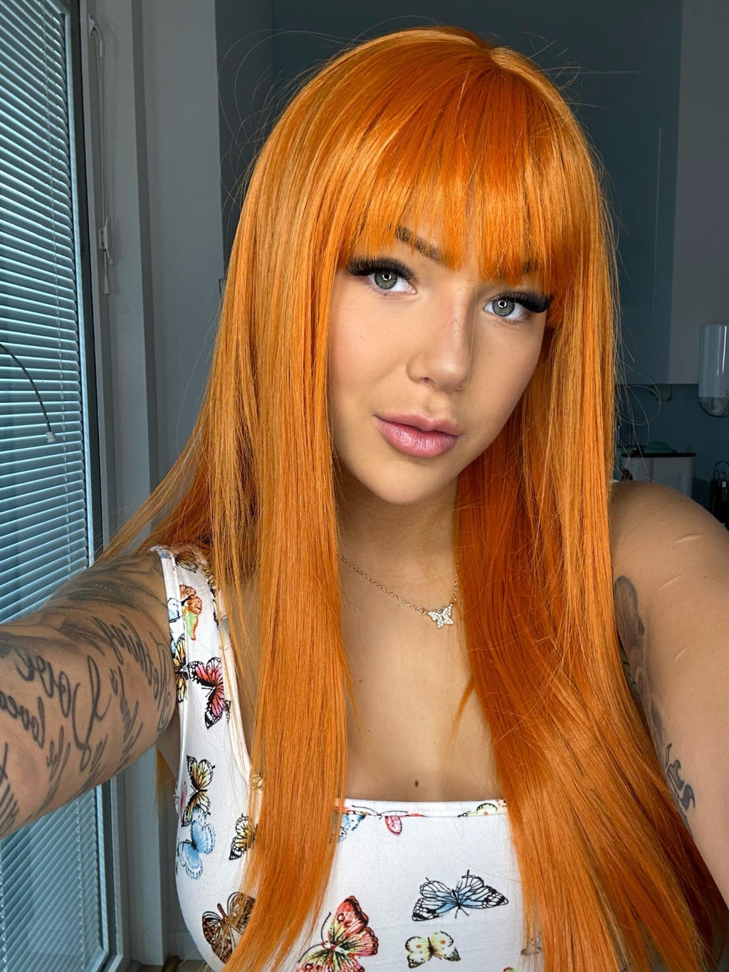 osefin Ottosson bär en orange peruk med lugg från Foshair Fahlen of Sweden. Peruken har en livlig, varm orange nyans och en modern frisyr med rak lugg, som ger en ungdomlig och energisk look.